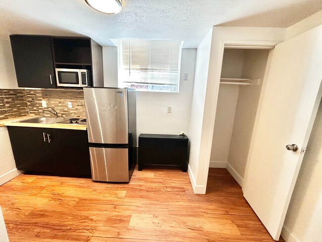 Contemporary kitchen with sleek stainless steel appliances, modern cabinetry, and elegant wood flooring, perfect for stylish urban living. - Plaza West