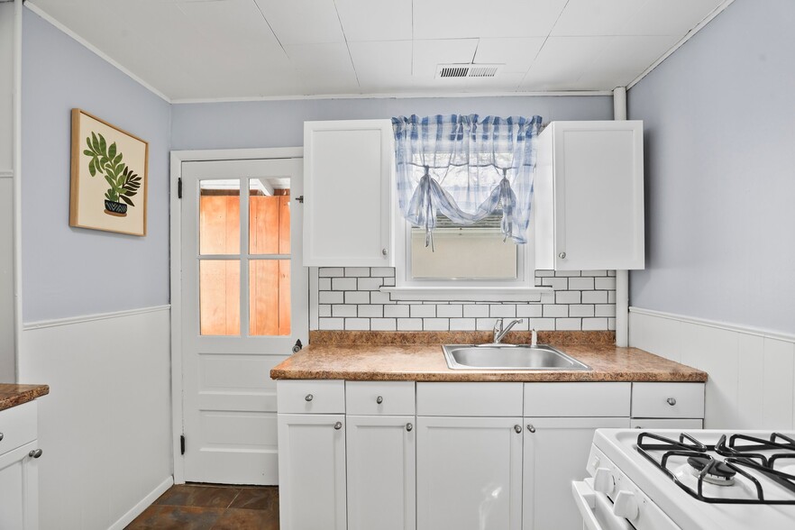 Kitchen with white cabinets and applicances, brand-new tile backsplash, and laminate countertop - 1710 B St