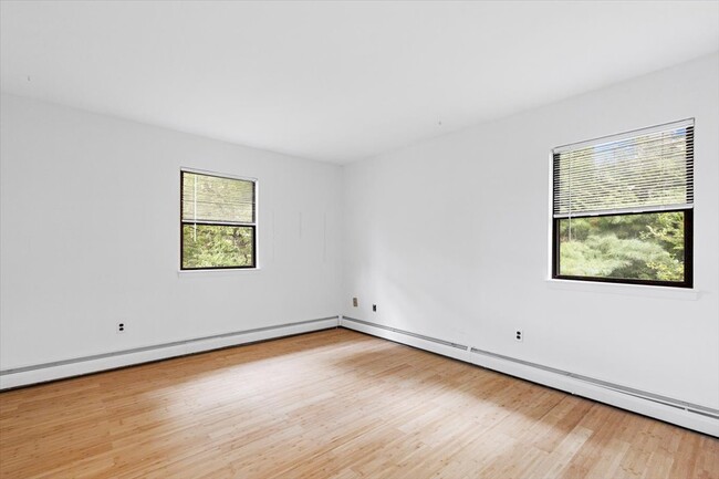 Primary bedroom with space for a queen-size bed, featuring two closets and windows. - 45 High St