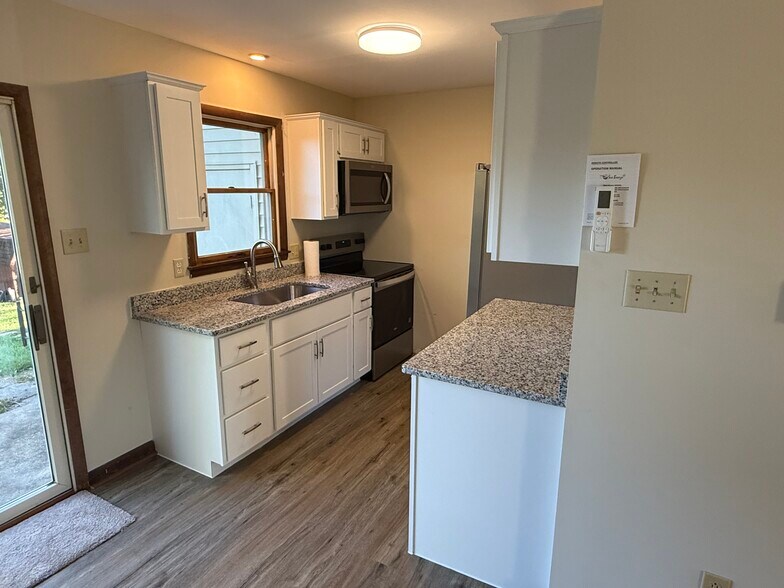 Modern kitchen features new cabinetry, granite countertops, and stainless steel appliances - 1004 Corbett St