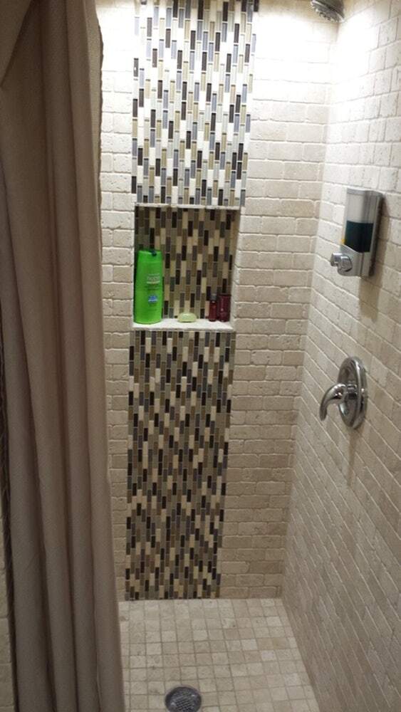 Shower with custom travertine tile in renovated full lower-level guest bathroom - 519 N Payne St