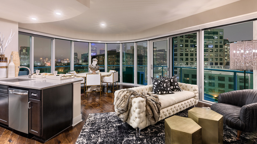 Living room with stunning views, hardwood flooring and floor to ceiling windows - One Uptown