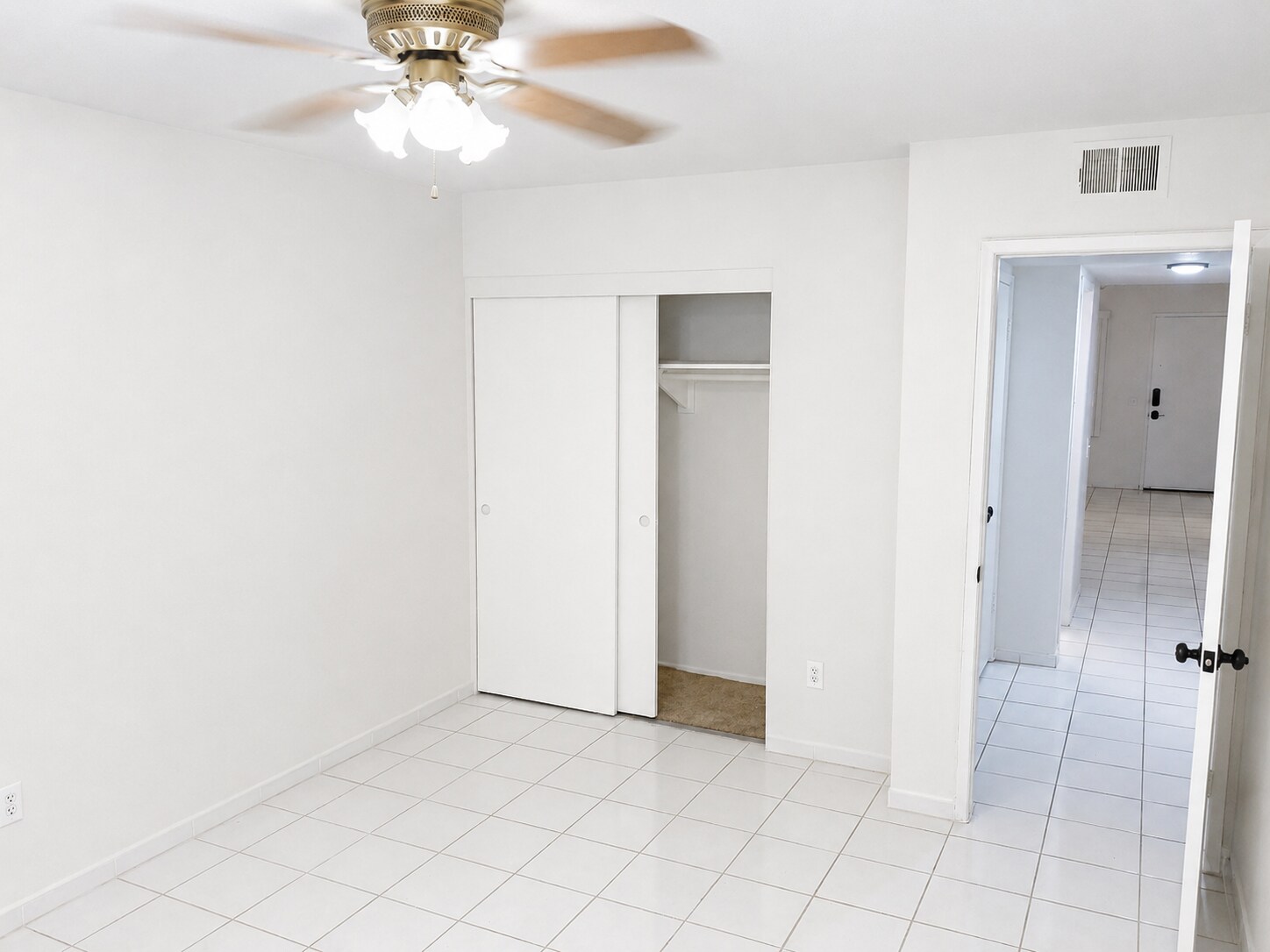 Bright bedroom with tile flooring, ceiling fan, and built-in closet access. - 339 E Taft Ave