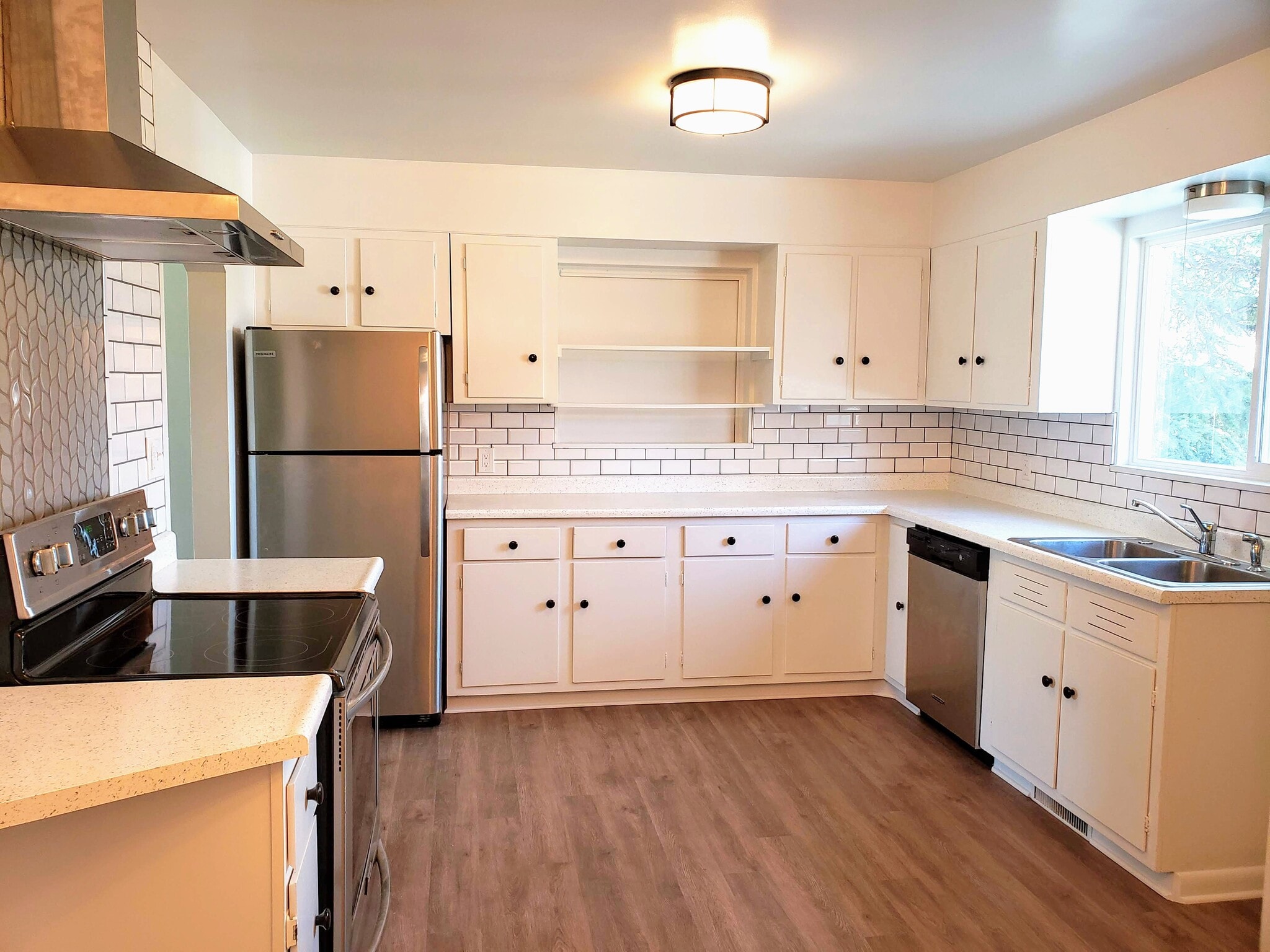 Updated kitchen with continuous luxury vinyl plank flooring, SS appliances, and gorgeous tile back-splash. - 3155 S Fox St