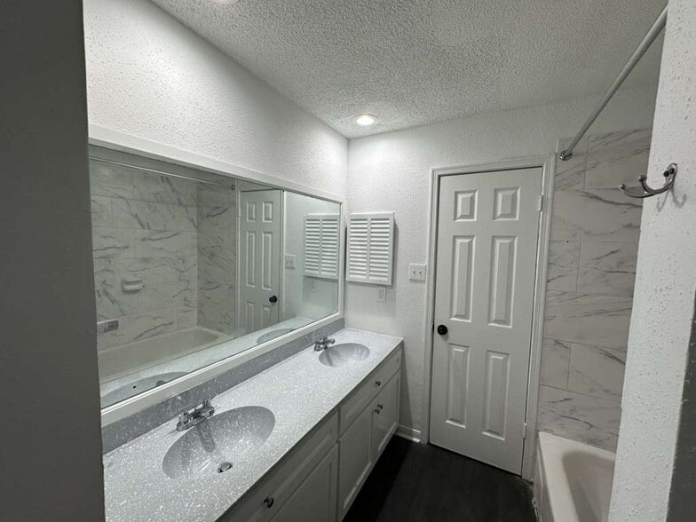 Primary Bathroom: Double vanity, soaking tub, and linen closet. - 7700 Creekbend Dr