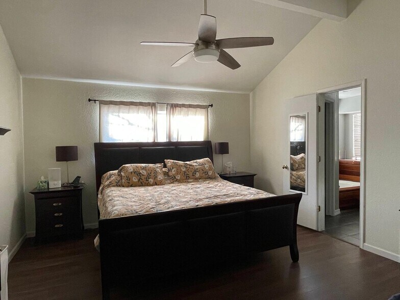 Spacious primary suite with king bed, large windows, and vaulted ceiling. - 2401 Thistle Ct