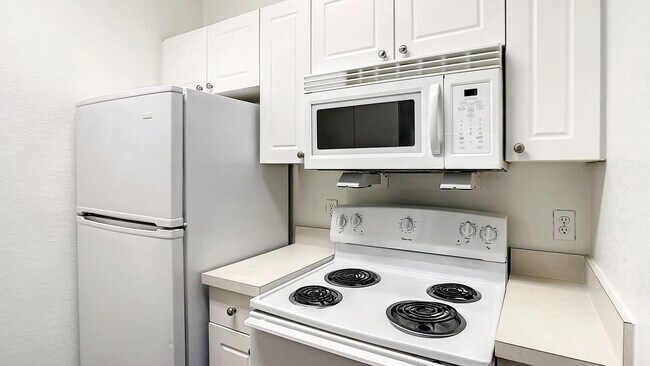 Step into an inviting kitchen featuring white appliances, ample cabinet storage, and durable countertops. - Charleston Cay