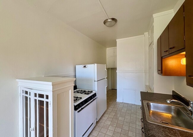Charming kitchen with classic appliances, a cozy layout, and warm wooden cabinetry. - Ivanhoe