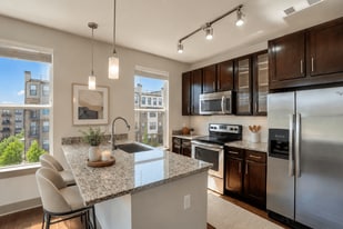 A modern kitchen with a granite countertop and stainless steel appliances. - ICON at Dulles