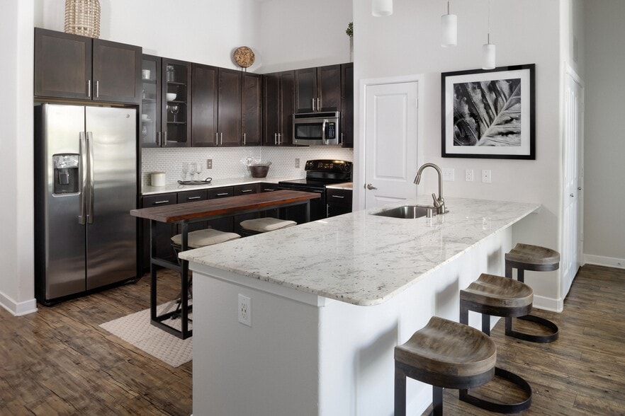 Kitchen with espresso cabinetry, granite countertops, tile backsplash, and stainless steel appliances - Avalon Lakeside