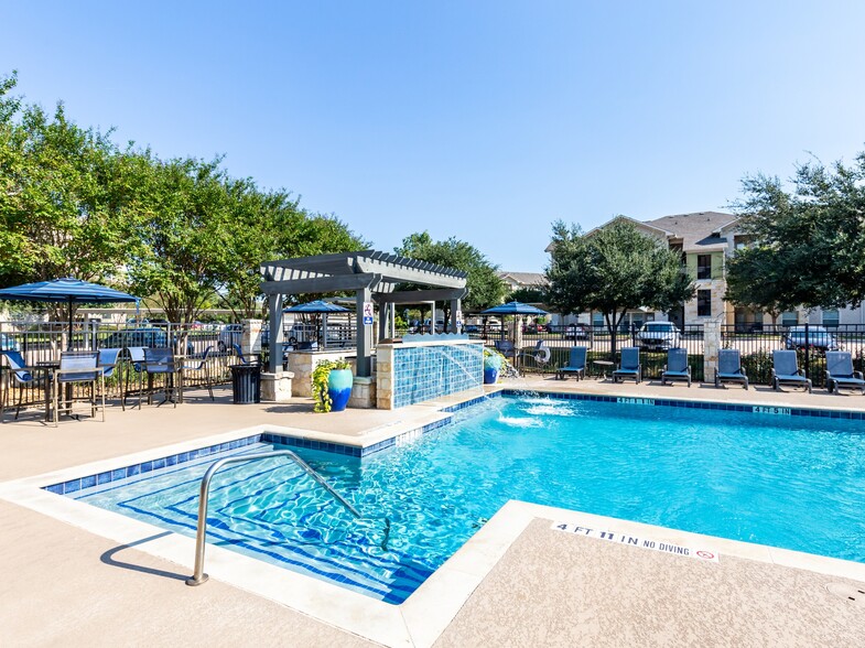 Lavish pool deck with serene water feature and lounge seating - Alister Oak Hill