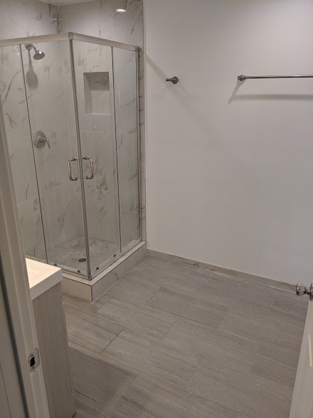 Glass-enclosed shower with marble tile detail - 6534 Peterson Ave