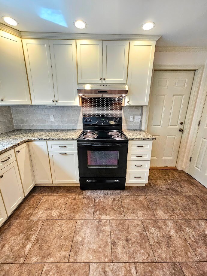 Electric stove with tile backsplash, door to garage - 30 Fairfield Ave