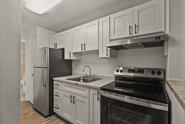 Sleek and functional kitchen featuring stainless steel appliances and fresh, modern finishes. - Rainier Gardens Aparments