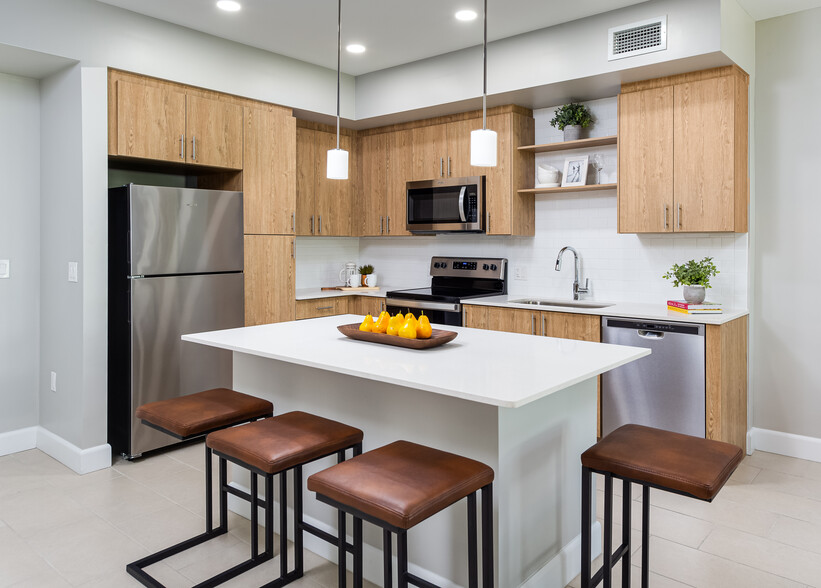 Open concept kitchen with quartz countertop, island, stainless steel appliances and tile backsplash - Avalon Doral