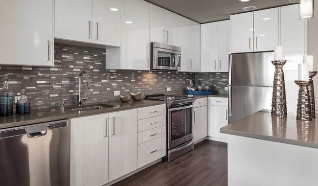 Modern kitchen featuring quartz countertops and stainless steel appliances - Indigo Apartments