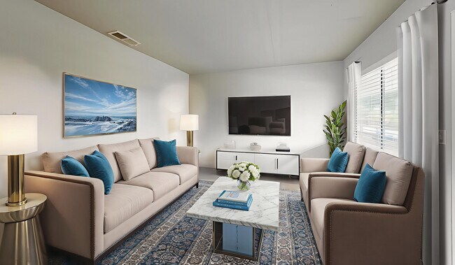 Chic modern living room with plush beige sofas, vibrant blue cushions, and a sleek marble coffee table. Elegant decor featuring stylish plants, artistic wall painting, and ample natural light. - Soto Apartments