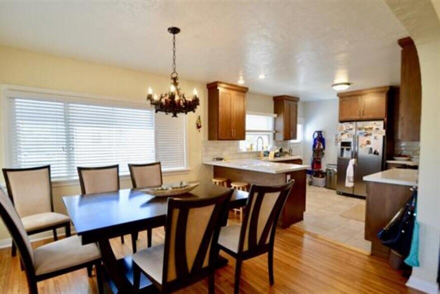 Kitchen/Dining with original wood floors, 1927 chandelier with dimmer, large windows with blinds facing front of home and driveway - 4770 Bancroft St