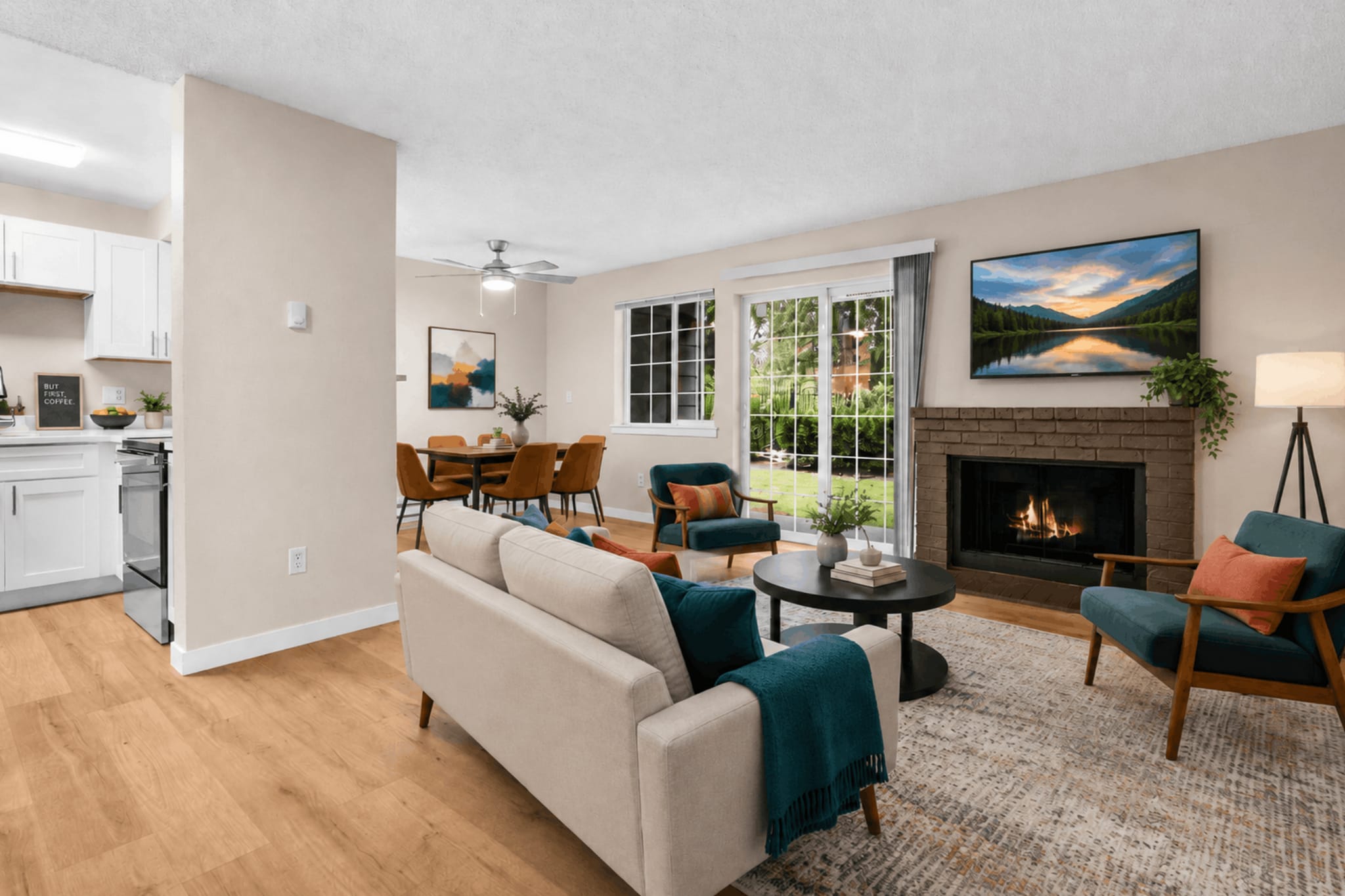 A warm and inviting living space with a cozy fireplace, direct patio access, and an open layout connecting the living room, dining area, and kitchen. - Crossroads at Meridian Apartments