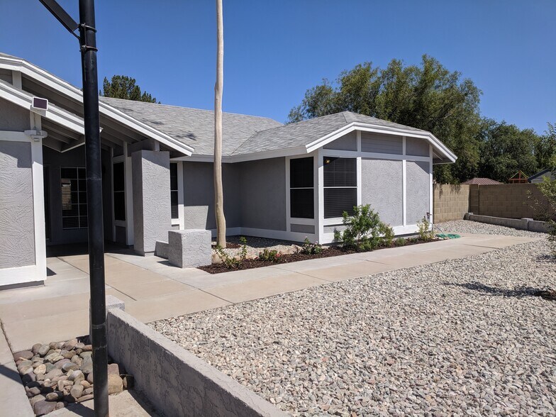 West Facing front of house, front bedroom windows, Grey granite rock, Shrubs and Trees for color. - 14101 N 78th Dr