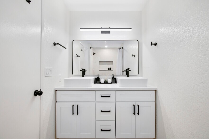 Bright bathroom with dual-sink vanity and sleek black hardware. - 1013 S Sunshine Ave