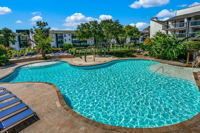 A sparkling, oversized pool surrounded by lush landscaping and scenic views. - Palatia Apartment Homes