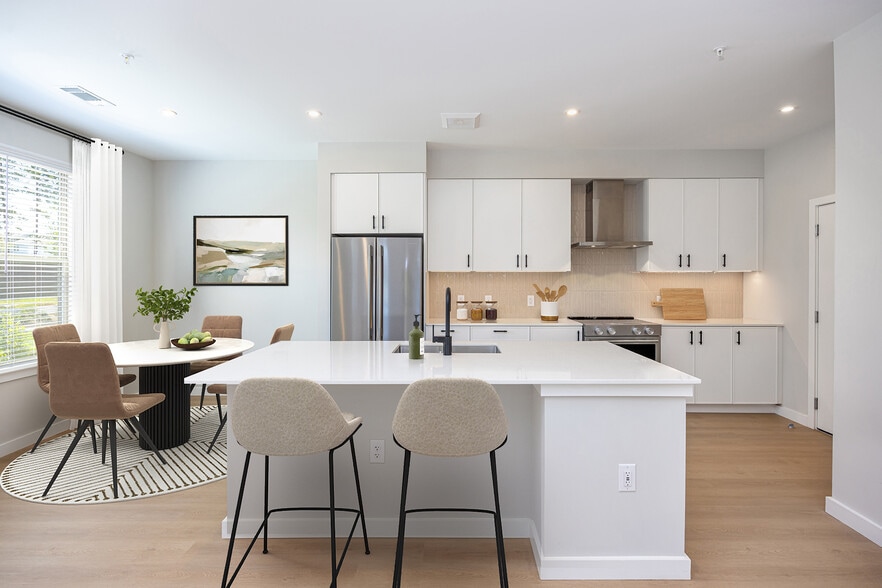 Upgrade Collection 3BR Townhome Kitchen with white cabinetry, white quartz countertops, and over-the-range hood - Avalon Brier Creek