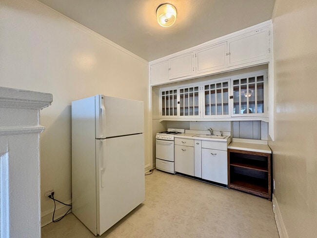 Charming vintage kitchen featuring classic white cabinetry, a spacious fridge, and cozy lighting. - Ivanhoe