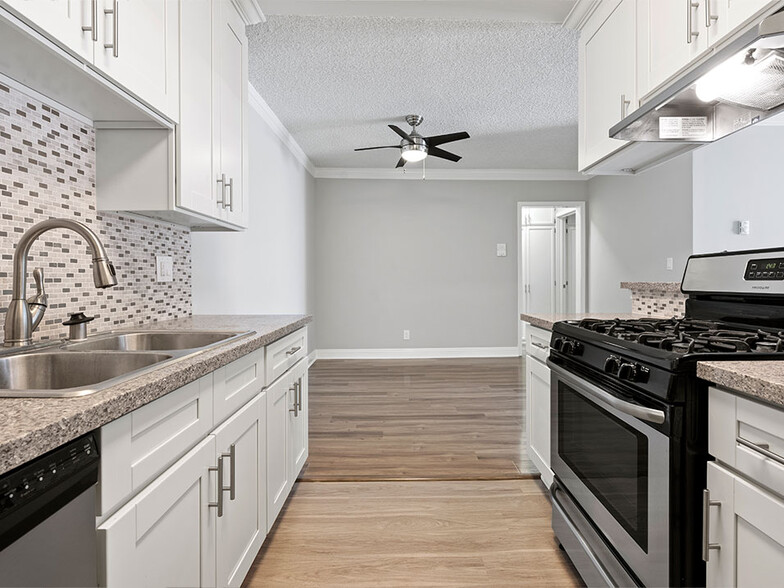 Custom tiled kitchen with stainless steel sink, oven, and fixtures. - Rose North