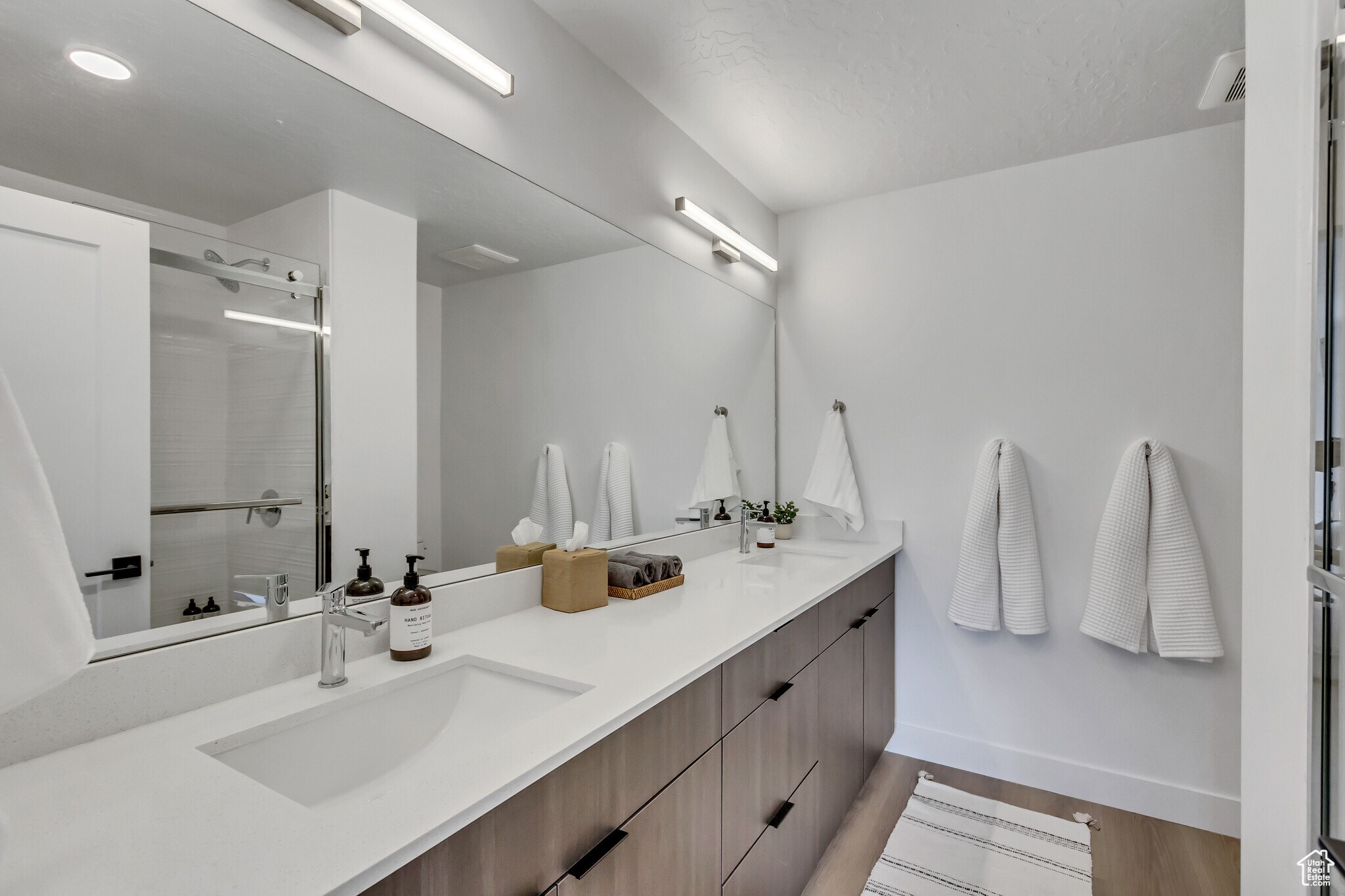 ensuite bathroom eaturing double vanity, a tile shower, and wood finished floors - 44 W Iko Ave