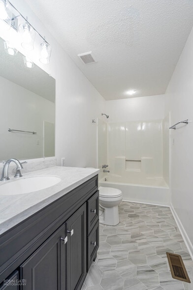 Hallway bathroom equipped with new tile, vanity, toilet, mirror and light fixtures - 502 Cherokee Court
