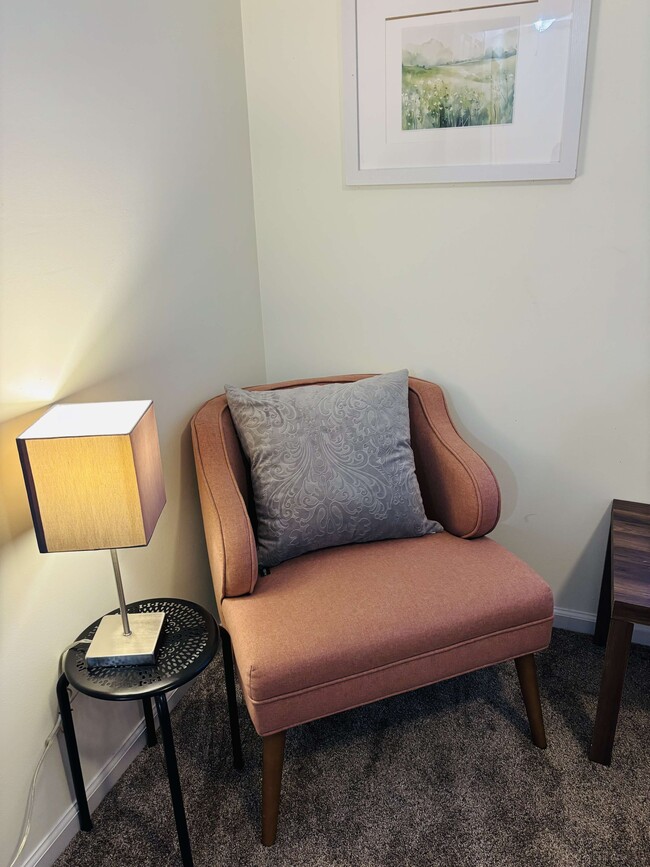 A cozy reading nook with a lamp and pillow. - 105 Lincoln Place Cir