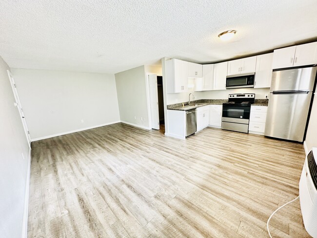 Experience the seamless blend of style and functionality in this open-concept kitchen and living area. - Hawk Point Apartments