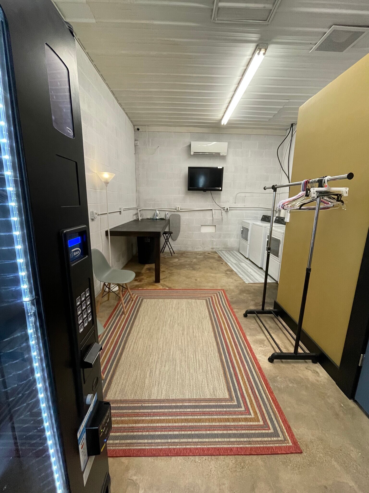 Folding area, tv, seating, and hanging area of laundry mat. - 475 S Hickory St