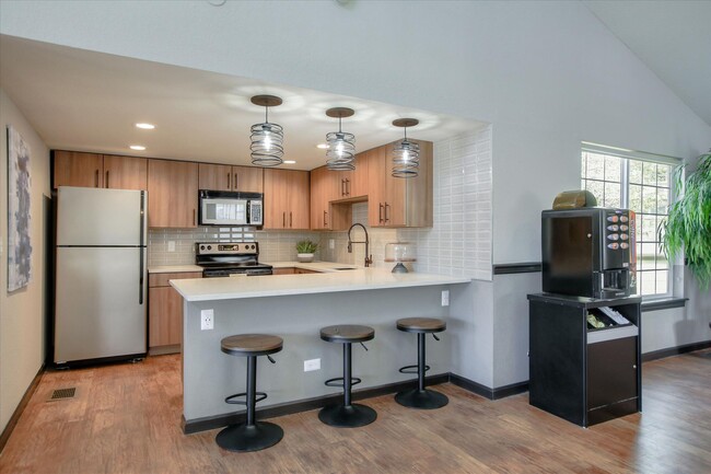 Image of the resident club house kitchen with stainless steel appliances quartz counters and stools. - Chestnut Ridge Apartment Homes