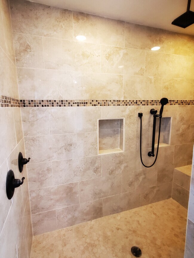 Walk-in shower with multiple shower heads and bench seating. - 37438 Meadowview Dr