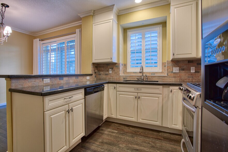 Kitchen with slab granite counters, gas stove, microwave, dishwasher, stainless appliances - 7422 E 7th Ave Unit 14