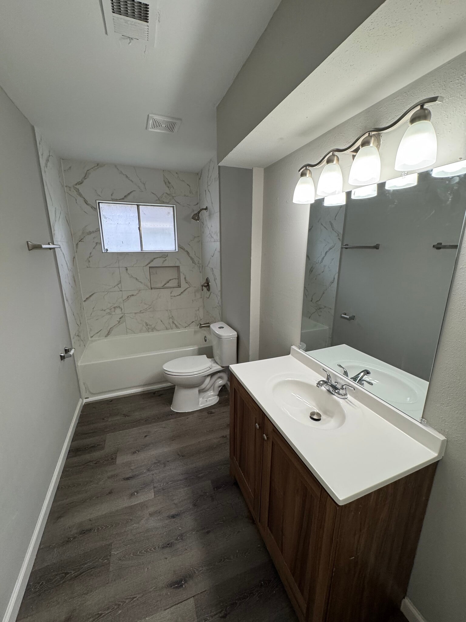 Spacious second bathroom with marble-look tile and warm wood cabinetry. - 11927 Troulon Dr