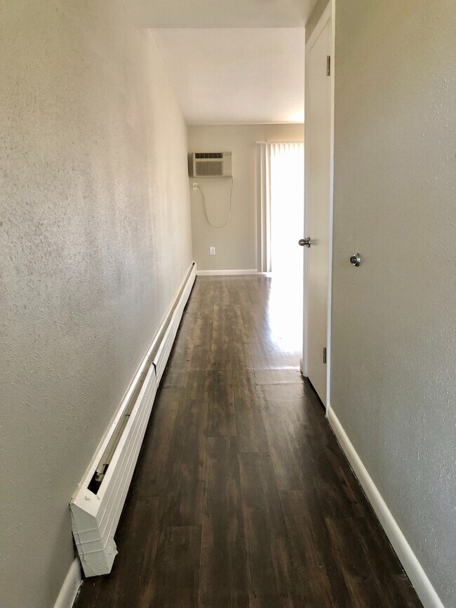 Experience the elegance of a chic hallway with warm wood floors and modern amenities. - GRACE LANDINGS APARTMENTS