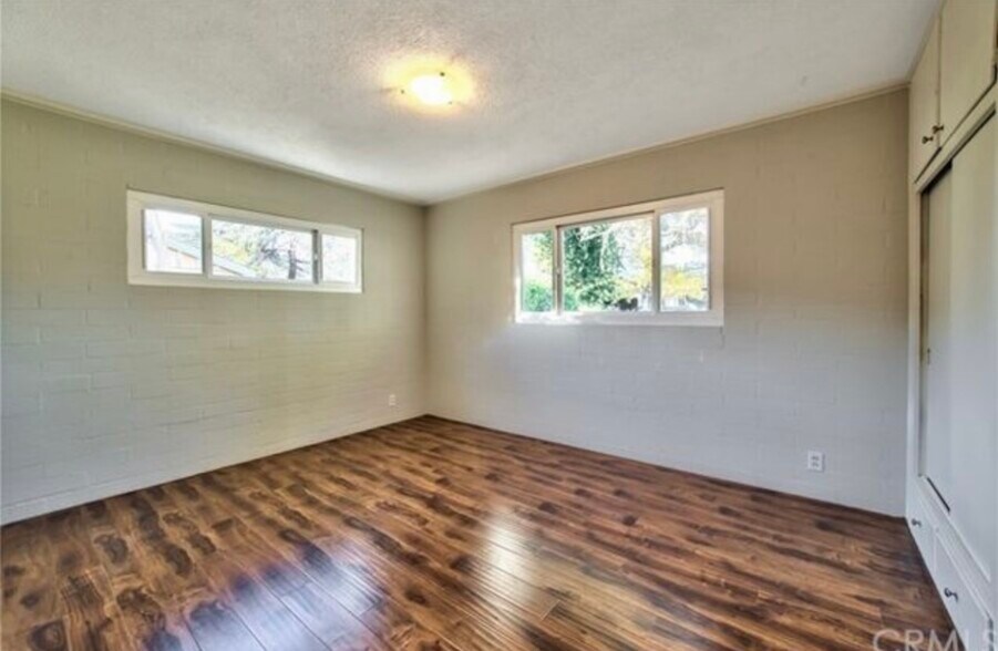 Spacious guest bedroom 1 with large closet and windows, offering a beautiful view of the front yard - 332 E Deodar St
