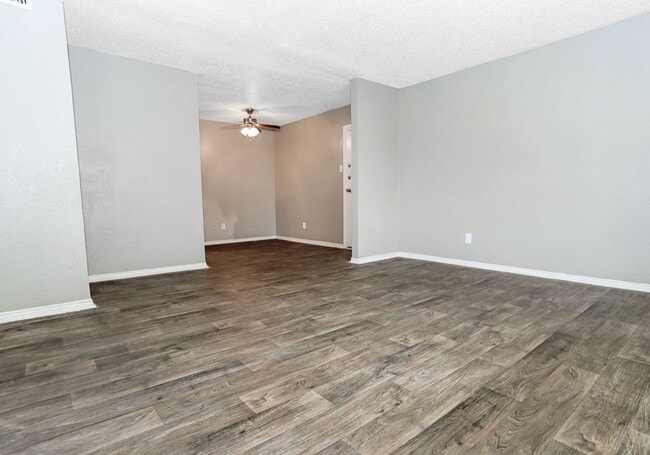Open-concept living area with wood-style flooring and natural light. - Sierra Nevada Apartments