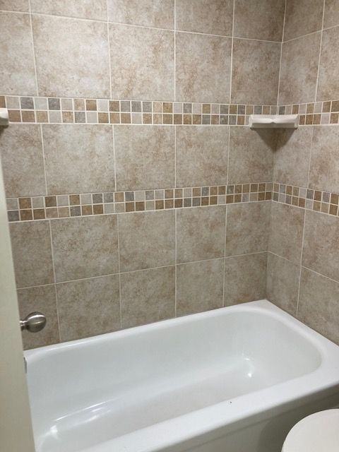 Experience relaxation in this elegantly tiled bathroom featuring a comfortable tub. - 5381 Delaware