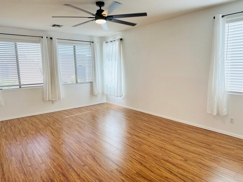 Bright primary bedroom with multiple windows and an updated ceiling fan. - 1177 W Laredo Ave