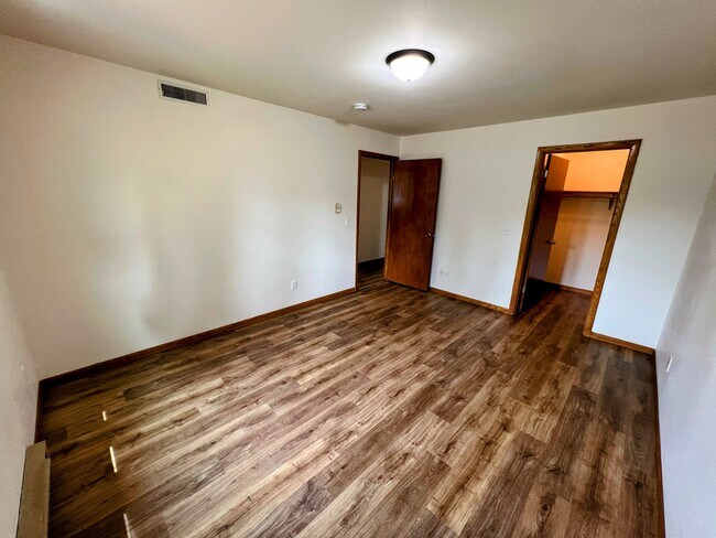primary bedroom with wood-style floors, large window, and plenty of space for a queen or king bed - 213 Ash Street