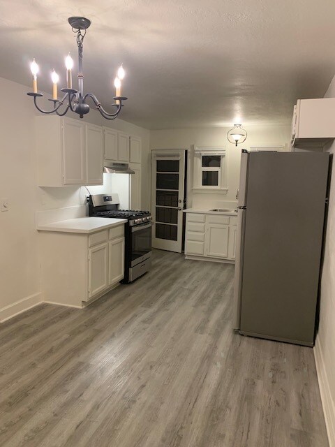View of the kitchen and front door from the dining room. - 24606 University Ave