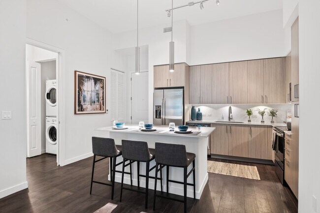 Kitchen with oak cabinetry, undercabinet lighting, white quartz countertops, and hard-surface vinyl plank flooring - Avalon Fort Lauderdale