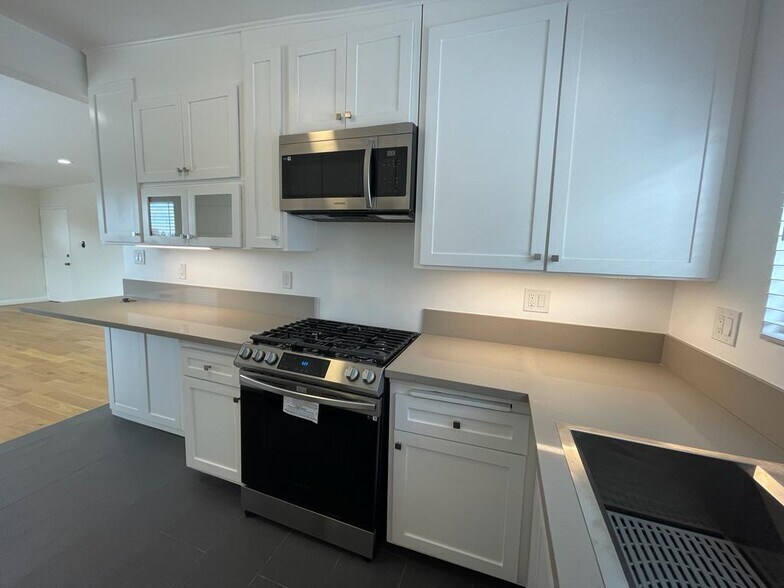 kitchen. stainless steel samsung gas range and microwave. under counter light - 7855 W Manchester Ave