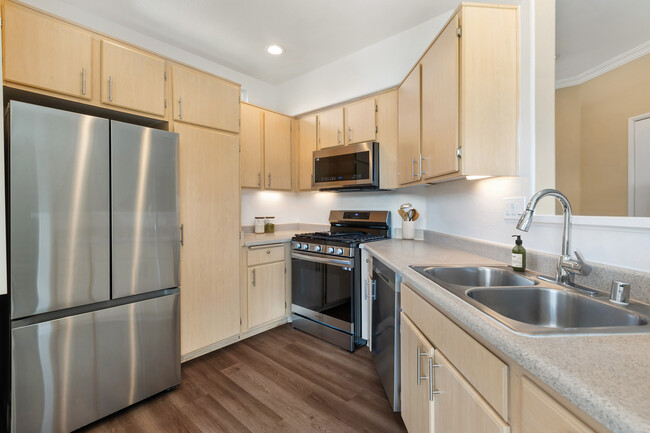 Updated Finishes kitchen with upgraded stainless steel appliances, laminate countertops, oak cabinetry, and upgraded hard surface flooring - Avalon Mission Oaks