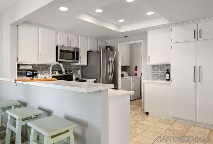 Kitchen with island and barstool seating, washer/dryer, leads to attached garage - 3086 Corte Trabuco