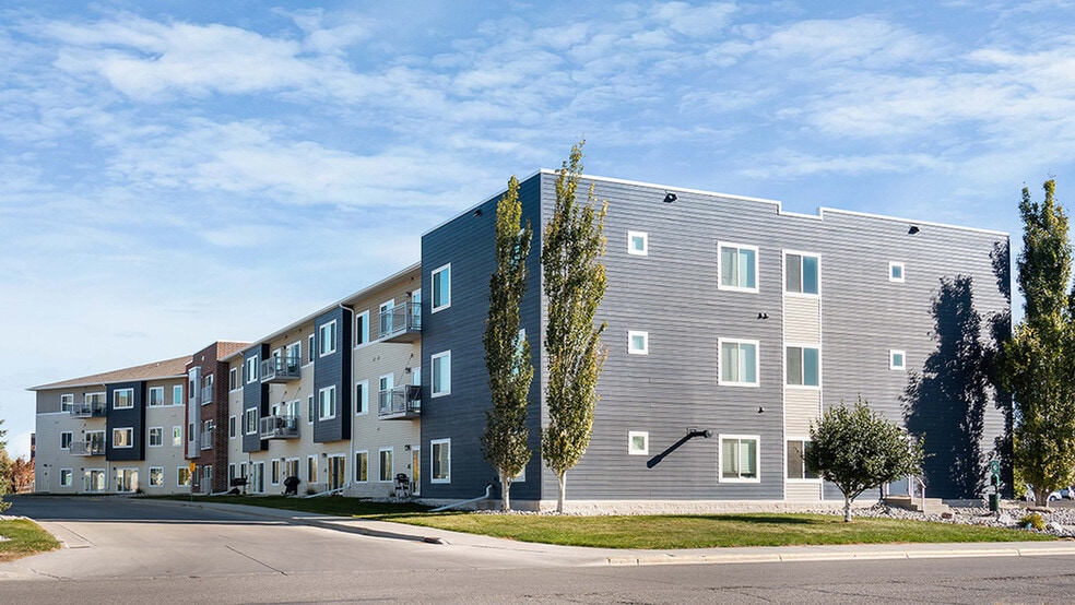 Modern apartment building with a sleek facade, featuring multiple balconies and surrounded by greenery, under a clear blue sky. - Mallview Apartments